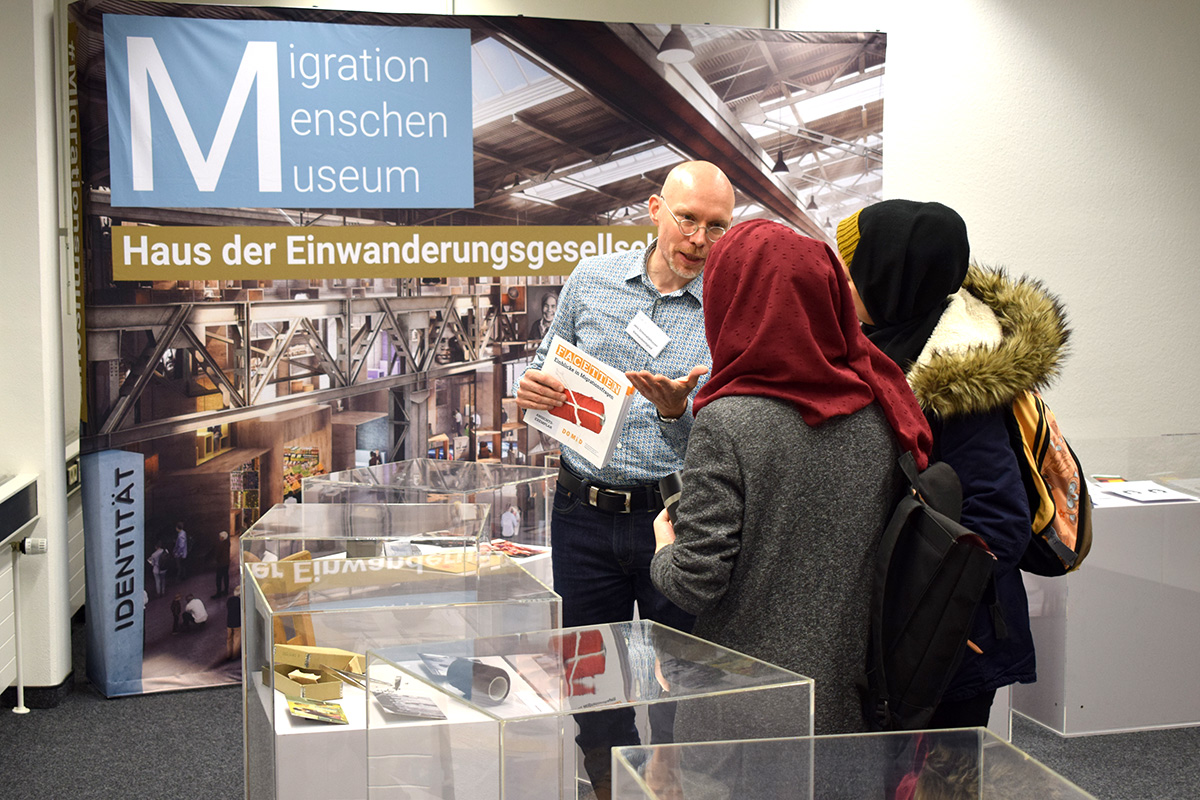 DOMiD-Vorstandsmitglied, Jens Grimmelijkhuizen, mit Besucher*innen der Ausstellung "Facetten" im Rahmen der Museumsnacht Köln 2019.