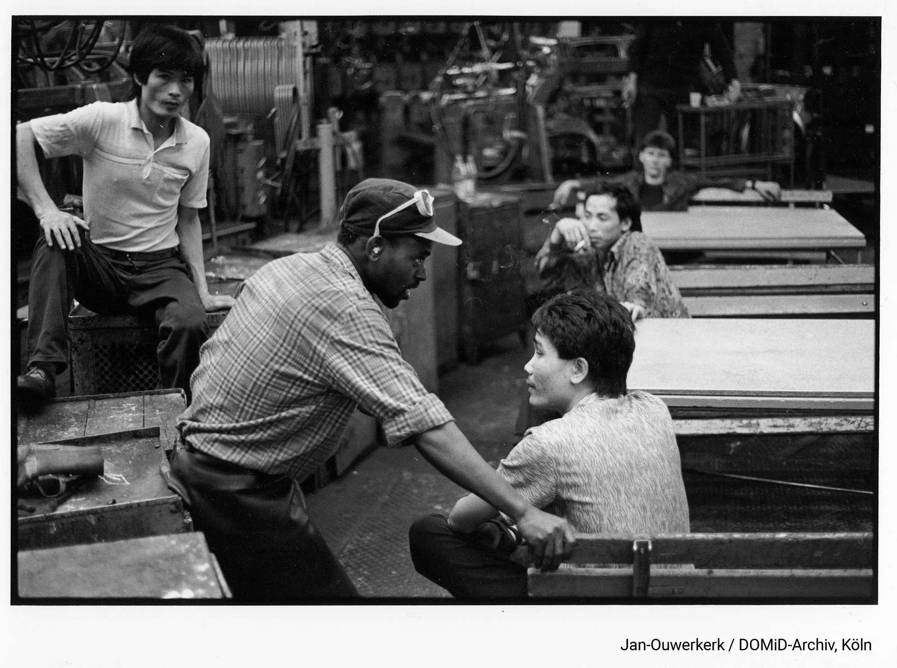 „Vertragsarbeiter“ in der Trabant-Fabrik in Zwickau, 1990. Bei Trabant arbeiteten ca. 11.800 Personen. Ein großer Anteil der Angestellten, die diese körperlich fordernde Arbeit leisteten, waren so genannte „Vertragsarbeiter“ aus anderen sozialistischen Ländern. Foto: Erik-Jan Ouwerkerk/DOMiD-Archiv, Köln, E 0111,0018