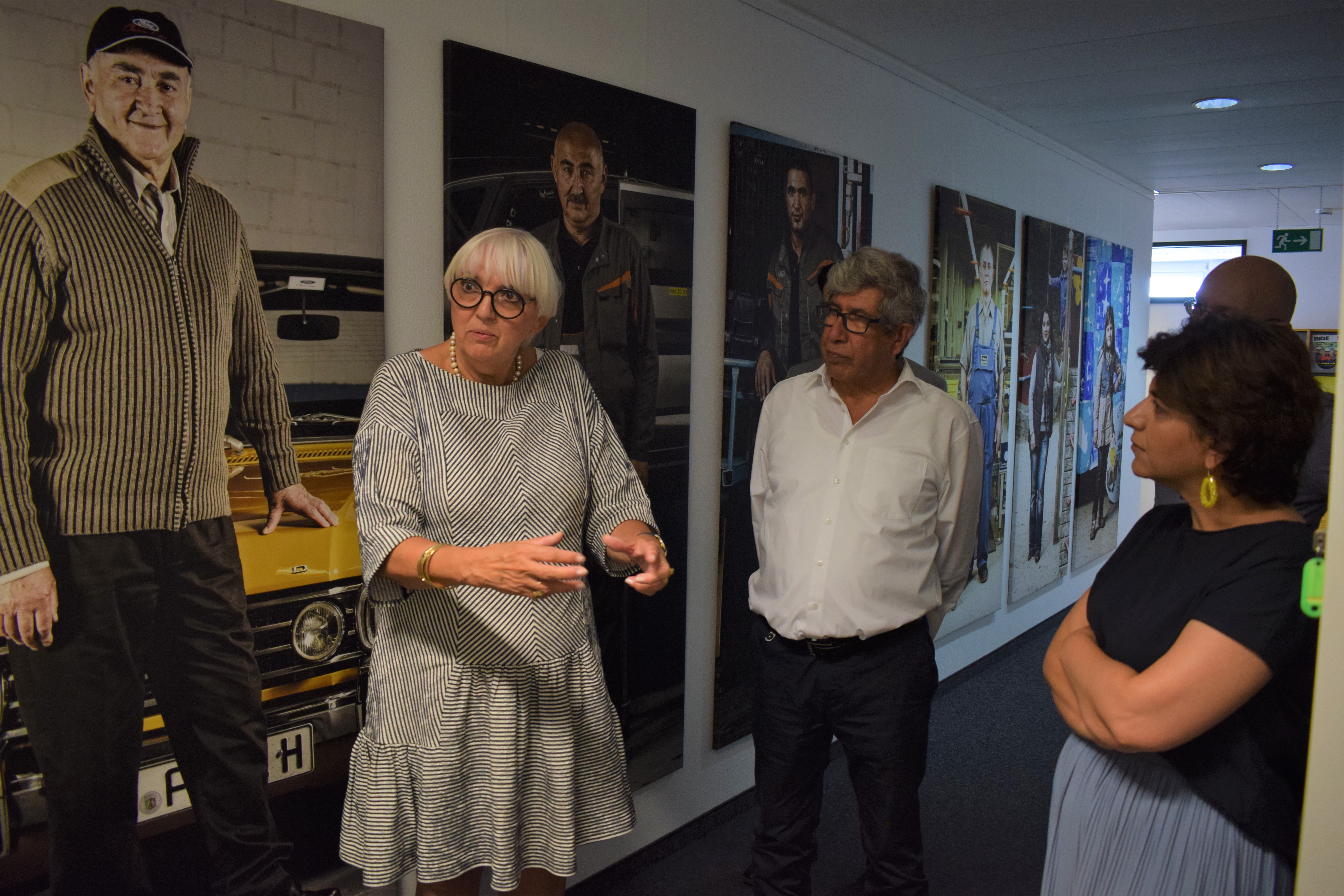 Minister of State for Culture Claudia Roth together with DOMiD board member Ahmet Sezer and Berîvan Aymaz. In the background you can see the photo exhibition "3 Generations" by Guenay Ulutuncok.