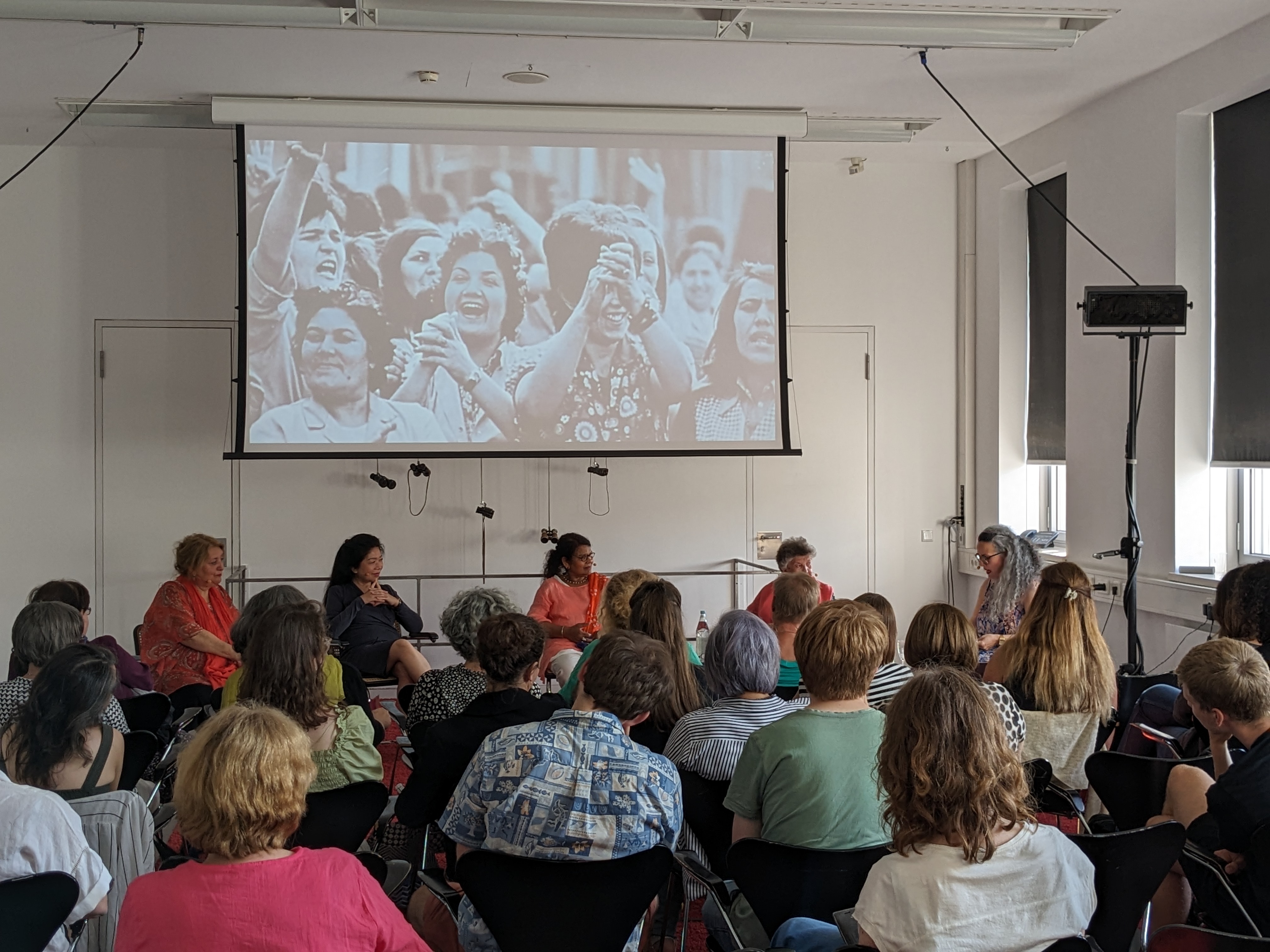 Talk at the Bundeskunsthalle "Give me the good life". Around 40 members of the audience listened to the stories of the former migrant workers. On the screen: a still from the film "Pierburg. Their struggle is our struggle. Photo: DOMiD Archive, Cologne